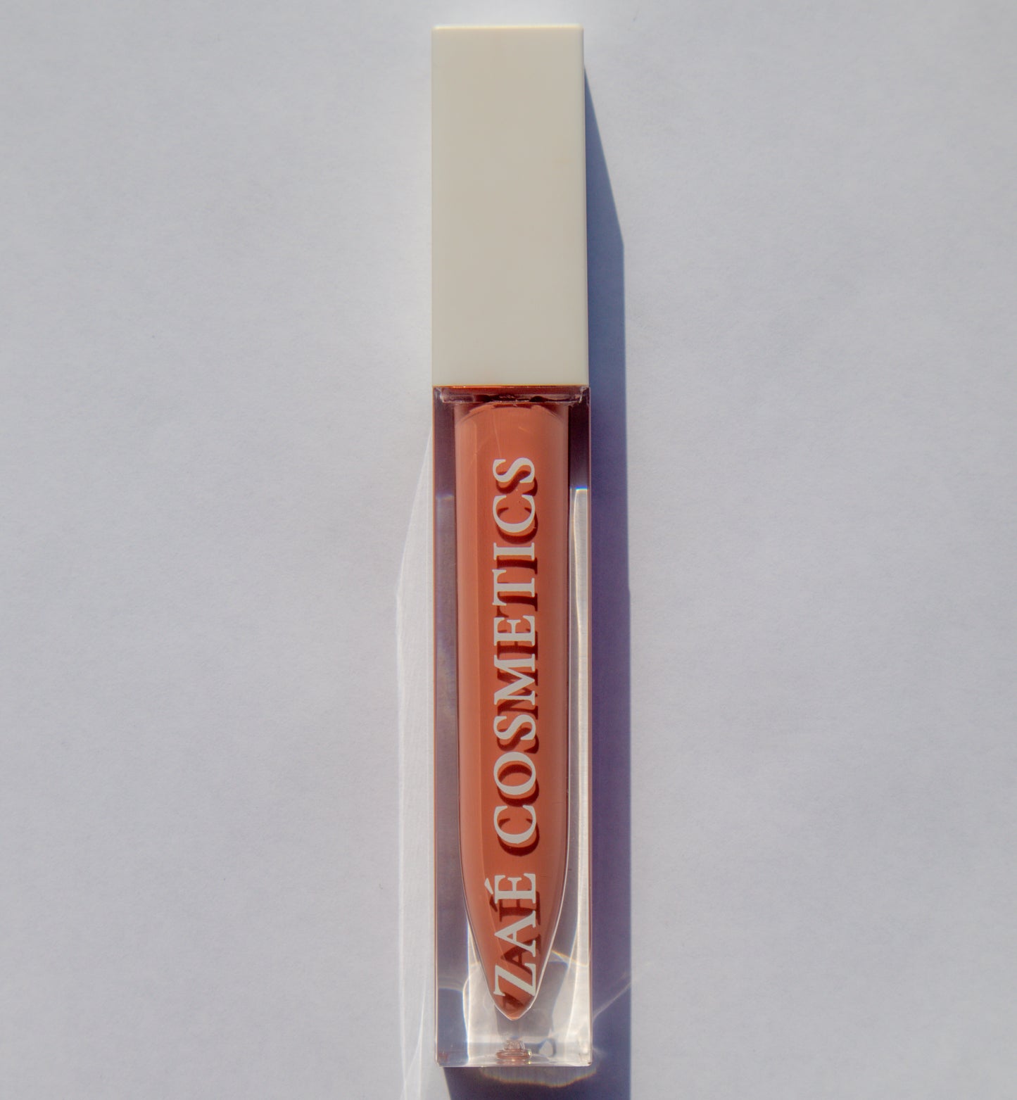Zaé vegan lip gloss hydrating formula"
"Zaé cruelty-free lip gloss tube applicator"
"Zaé lip gloss swatches on hand"
"Zaé lip gloss packaging sustainable beauty