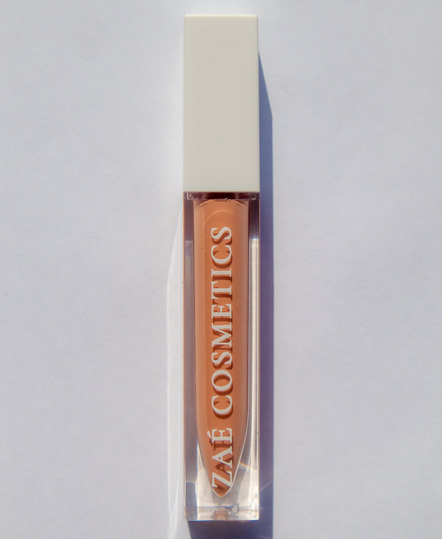 Zaé vegan lip gloss hydrating formula"
"Zaé cruelty-free lip gloss tube applicator"
"Zaé lip gloss swatches on hand"
"Zaé lip gloss packaging sustainable beauty