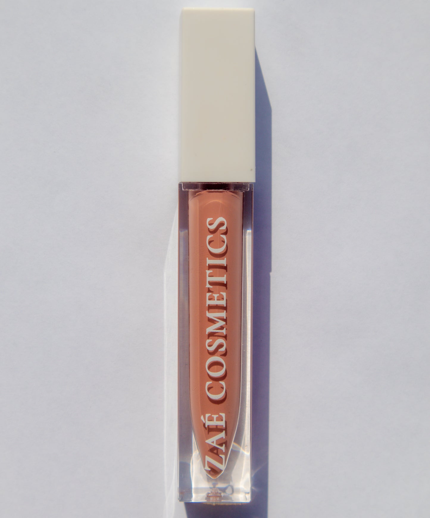 Zaé vegan lip gloss hydrating formula"
"Zaé cruelty-free lip gloss tube applicator"
"Zaé lip gloss swatches on hand"
"Zaé lip gloss packaging sustainable beauty