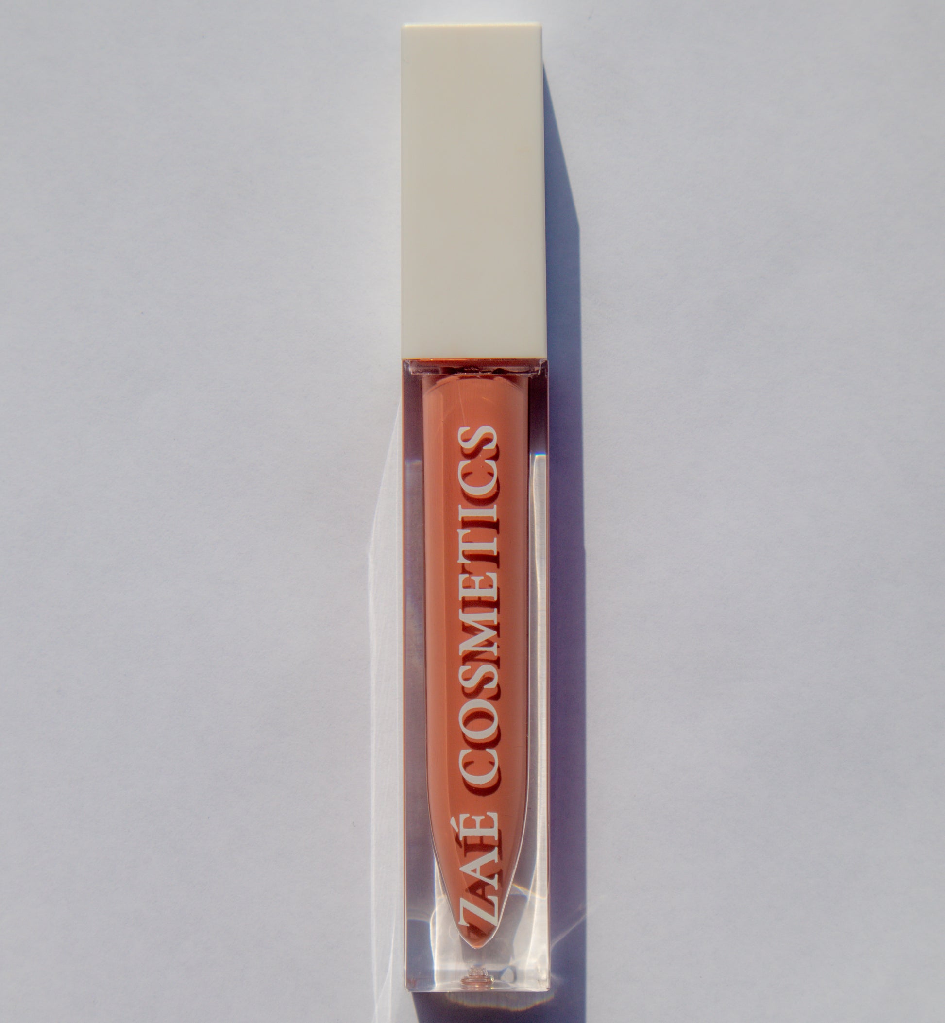 Zaé vegan lip gloss hydrating formula"
"Zaé cruelty-free lip gloss tube applicator"
"Zaé lip gloss swatches on hand"
"Zaé lip gloss packaging sustainable beauty