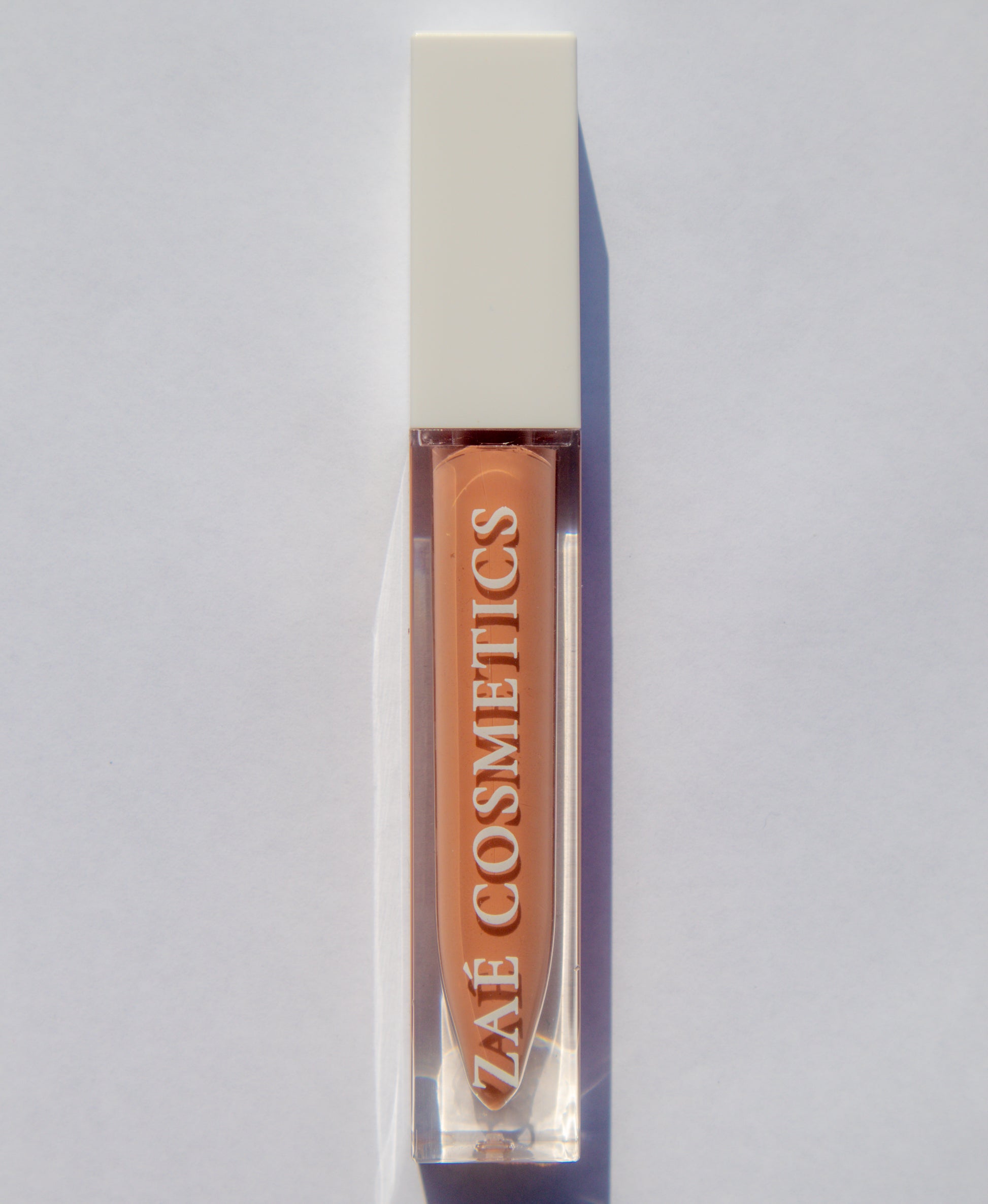 Zaé vegan lip gloss hydrating formula"
"Zaé cruelty-free lip gloss tube applicator"
"Zaé lip gloss swatches on hand"
"Zaé lip gloss packaging sustainable beauty